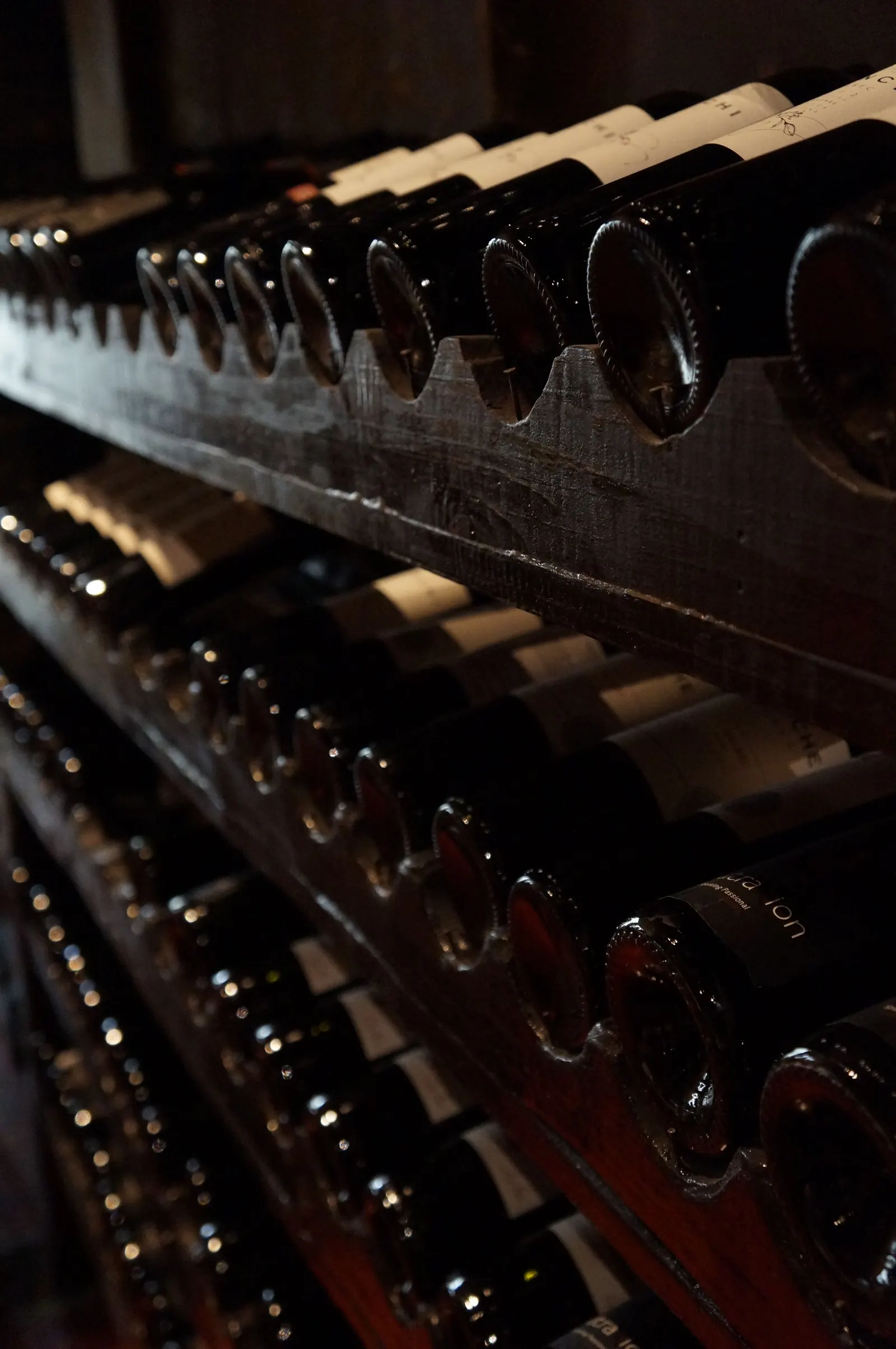 Wine bottles on wooden shelves in a dim cellar